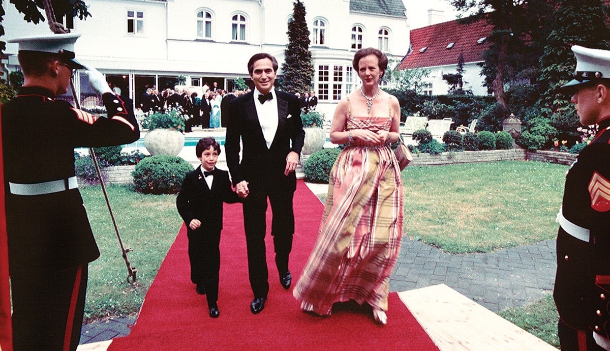 Ambassador John L. Loeb, Jr., his son, and Queen Margrethe II of Denmark attend an event at the US ambassador's residence in Rydhave, Denmark.